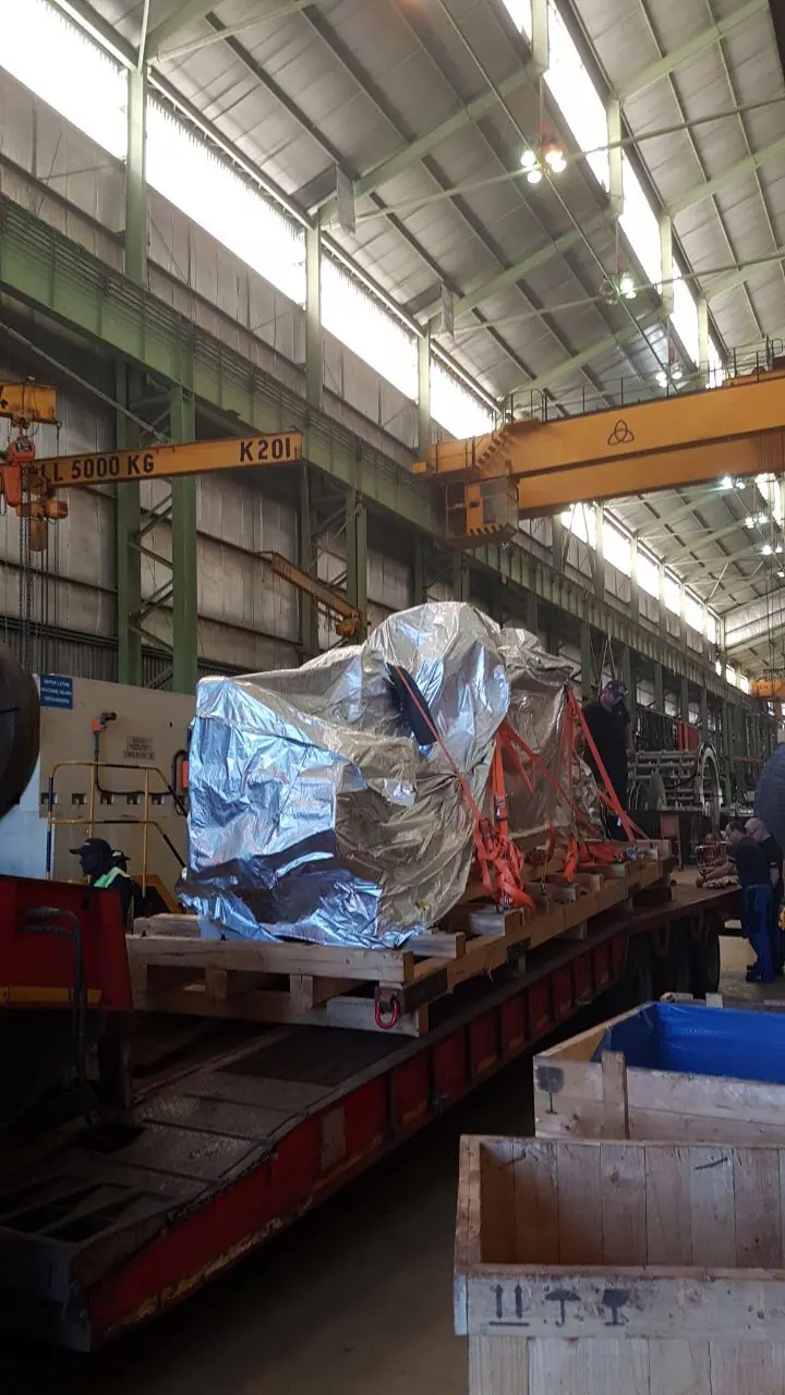 Large machine component being positioned during unloading